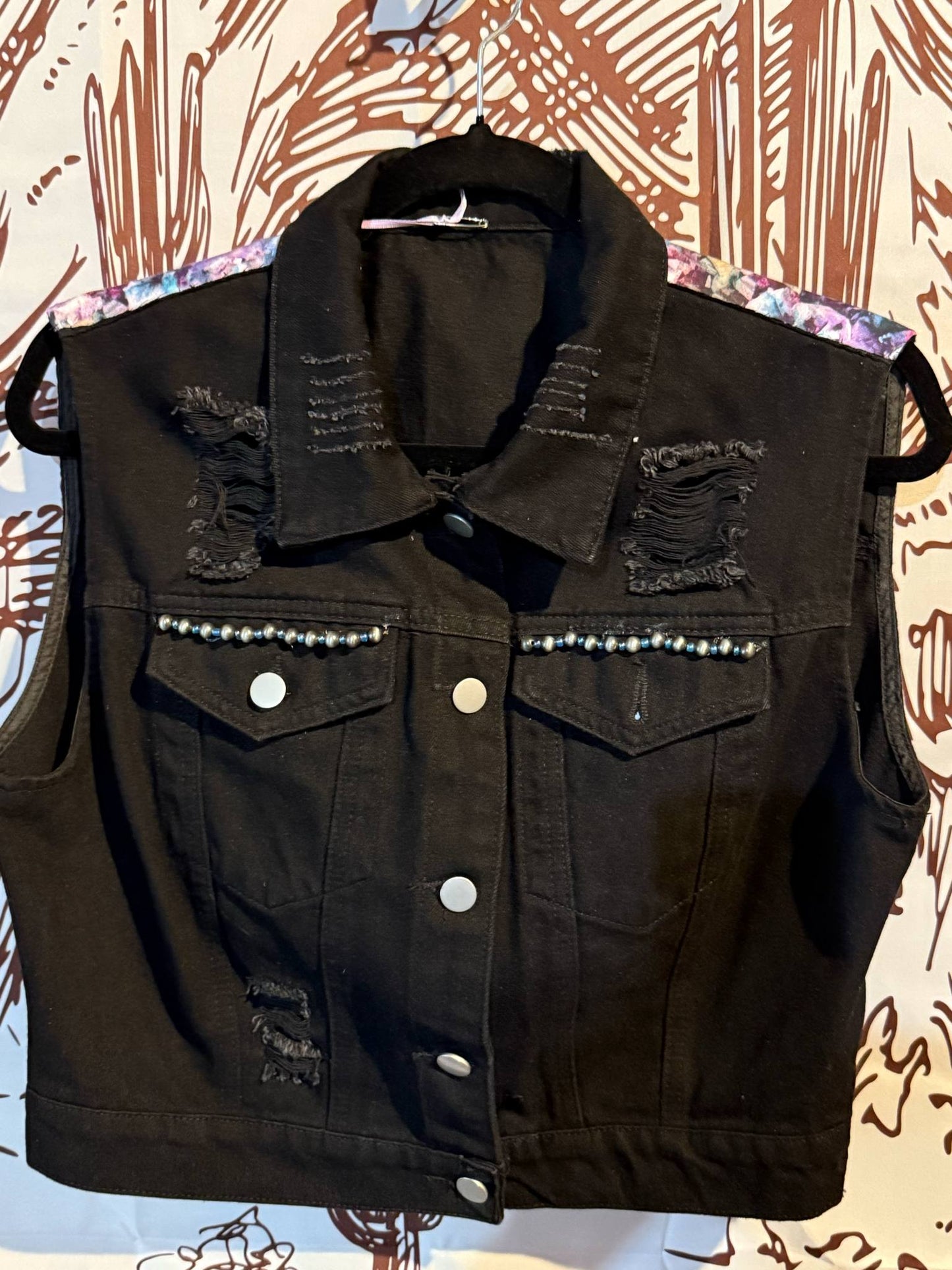 Black distressed denim vest with pearl beading across the chest and a floral-print lining on the shoulders, size L