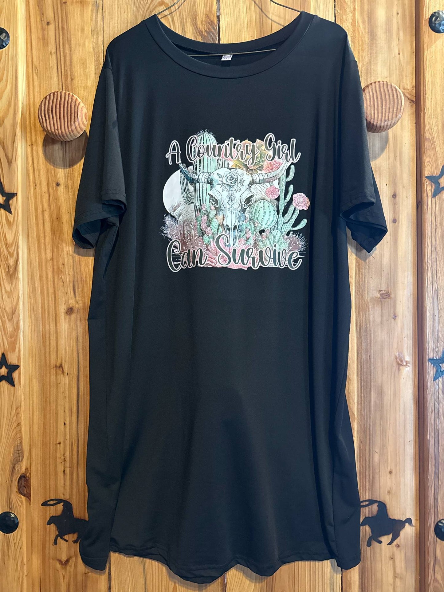 Black t-shirt with pastel western graphic featuring a longhorn skull, cactus, flowers, and the phrase “A Country Girl Can Survive”