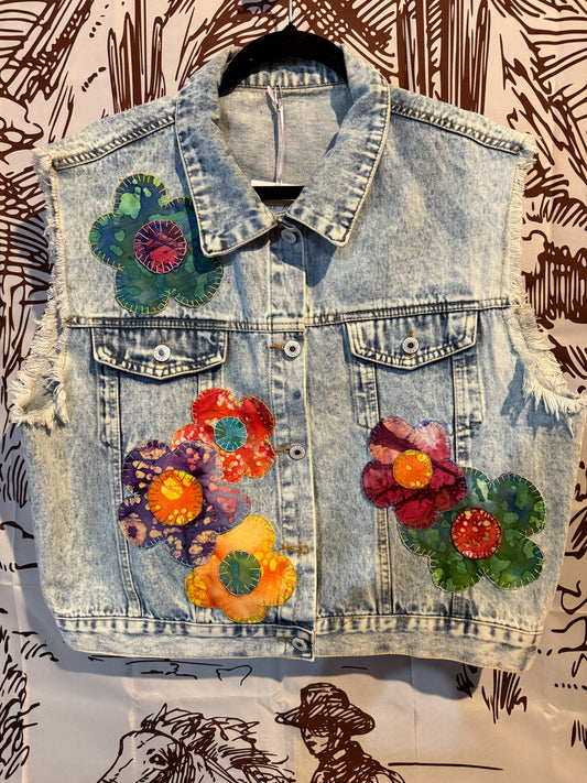 Front View: Light wash denim vest with multicolor retro floral appliqués and frayed sleeves, XXL