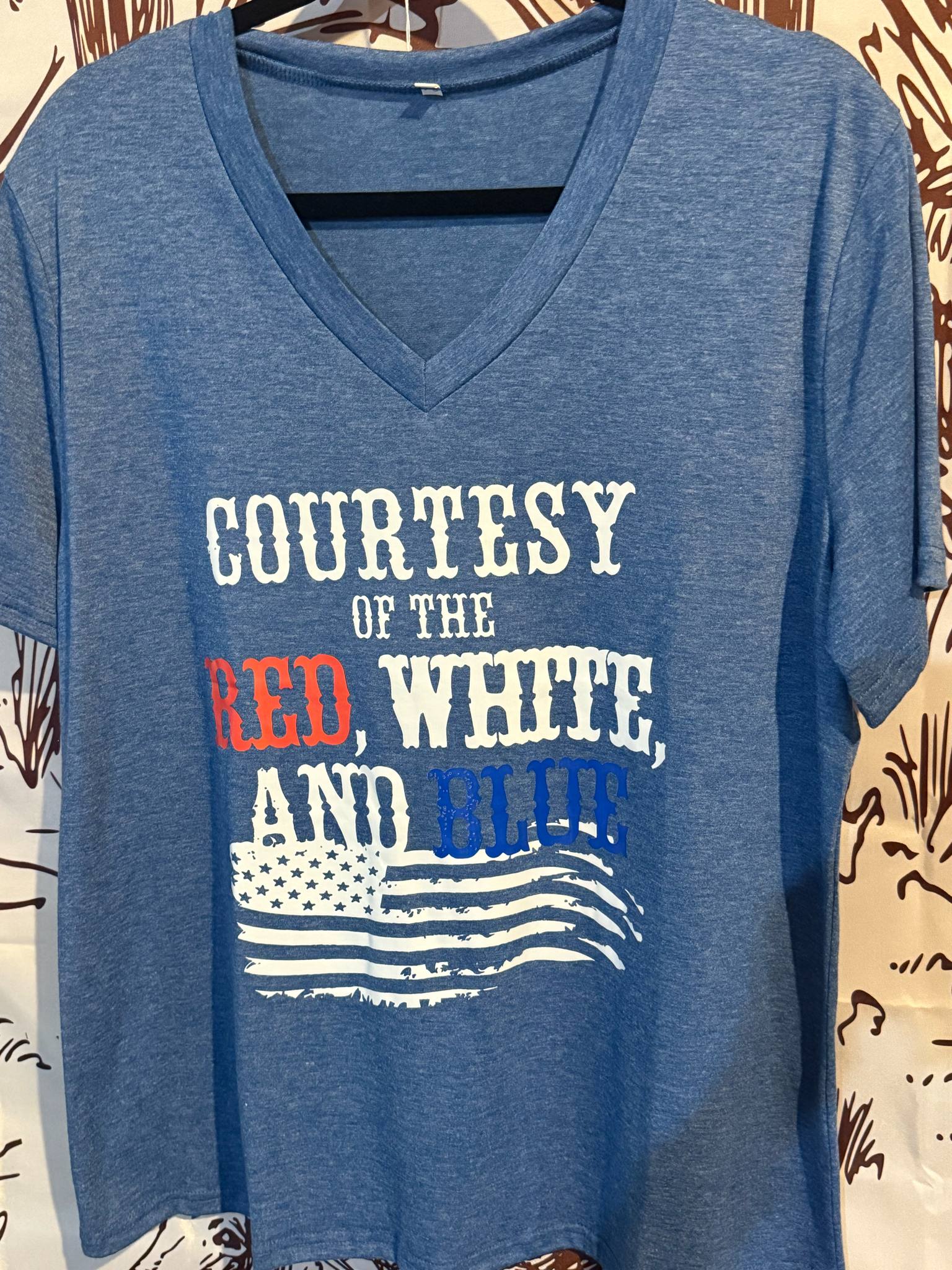 Heather blue adult v-neck t-shirt with a distressed American flag and bold “Courtesy of the Red, White, and Blue” text in patriotic colors.
