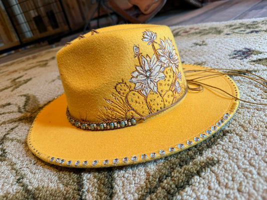 Yellow hand-burnt fedora hat with cactus floral design, gemstone band, and stitched brim from the Amira Collection.