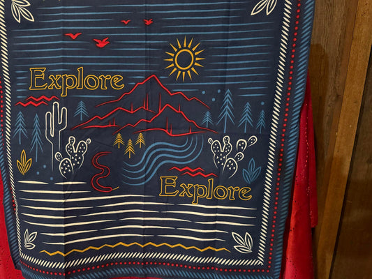 Blue cowboy scarf with red, yellow, and white illustrations of a desert landscape and “Explore” text.