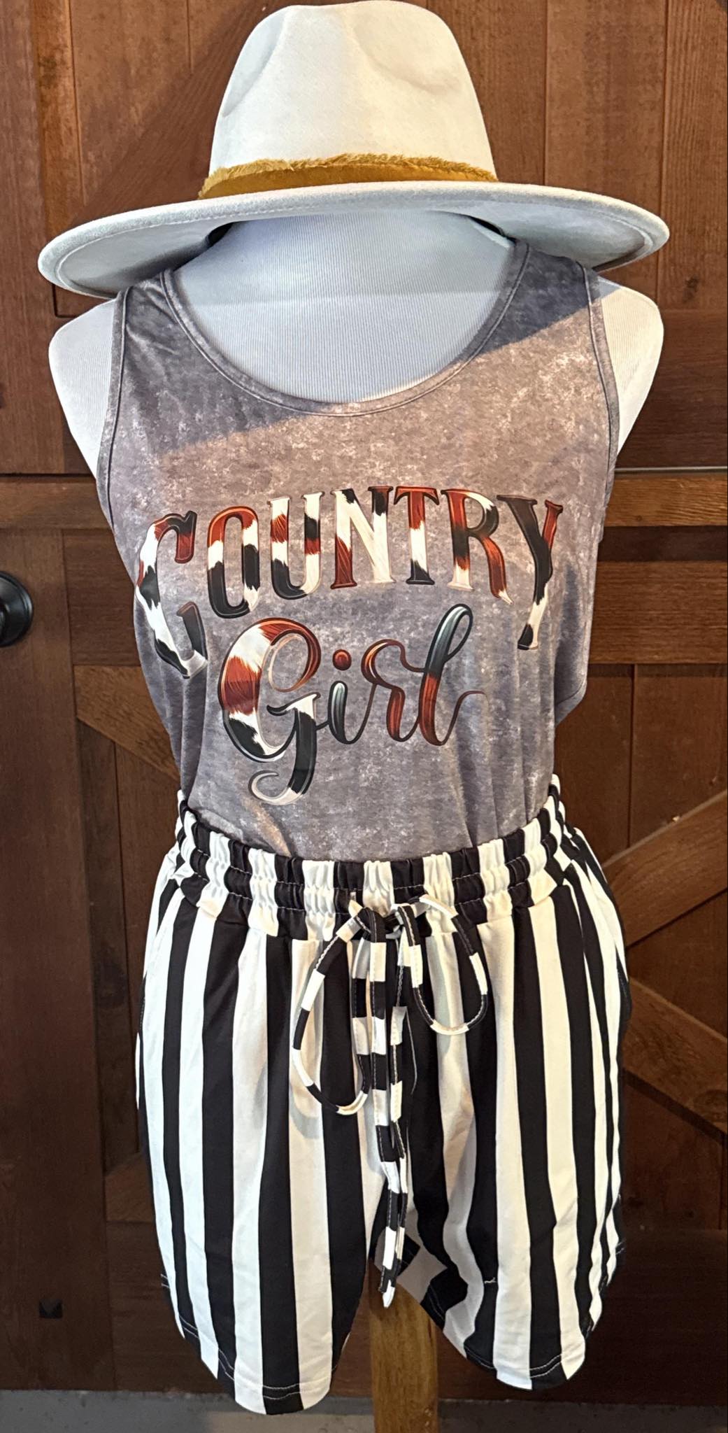 Washed grey sleeveless tank top featuring the words "Country Girl" in bold lettering with a cowhide-style graphic fill.