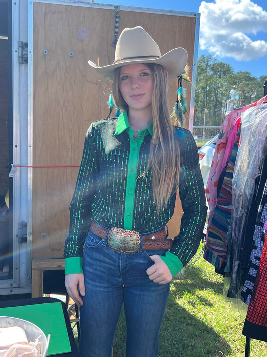 Cowgirl wearing a sheer, stretchy, lightweight green shimmer show shirt with jeans, a belt buckle, and a cowboy hat at an outdoor event.