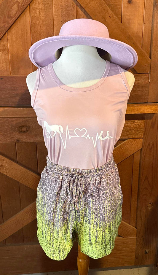 Lavender racerback tank top featuring a white graphic of a heartbeat line transforming into a horse, heart, and horseshoe, styled on a mannequin with lime ombré shorts and a wide-brim lavender hat.