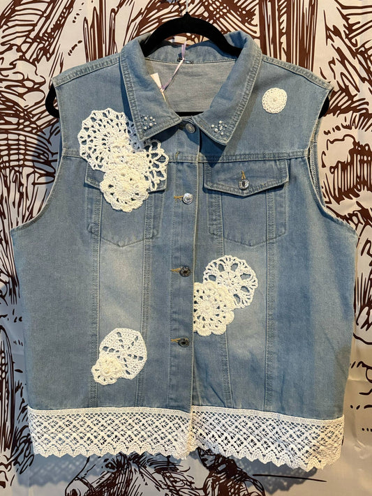 Front View: Light denim vest with white crocheted doilies and vintage lace trim along the hem, size XXL