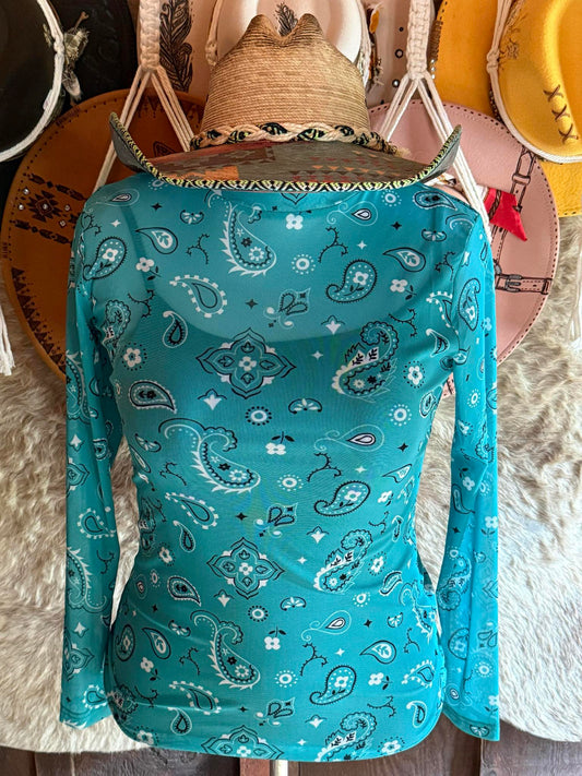 Teal long-sleeve mesh top with black and white western bandana print, displayed on a mannequin with hats in the background.