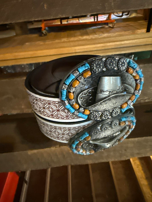 Western-style belt with an oversized buckle featuring turquoise and wood bead accents, silver detailing, and cowboy hat engraving.